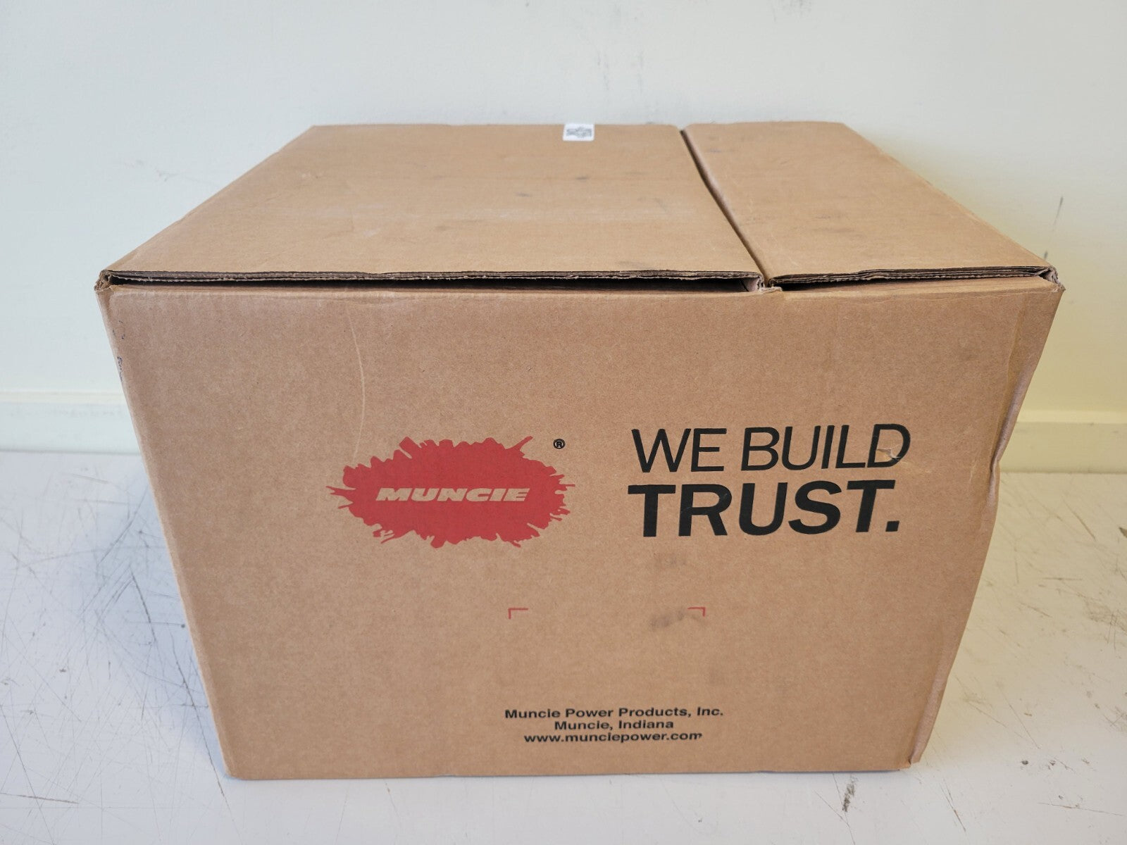 Cardboard box with Muncie logo and 'We Build Trust' text on a white background