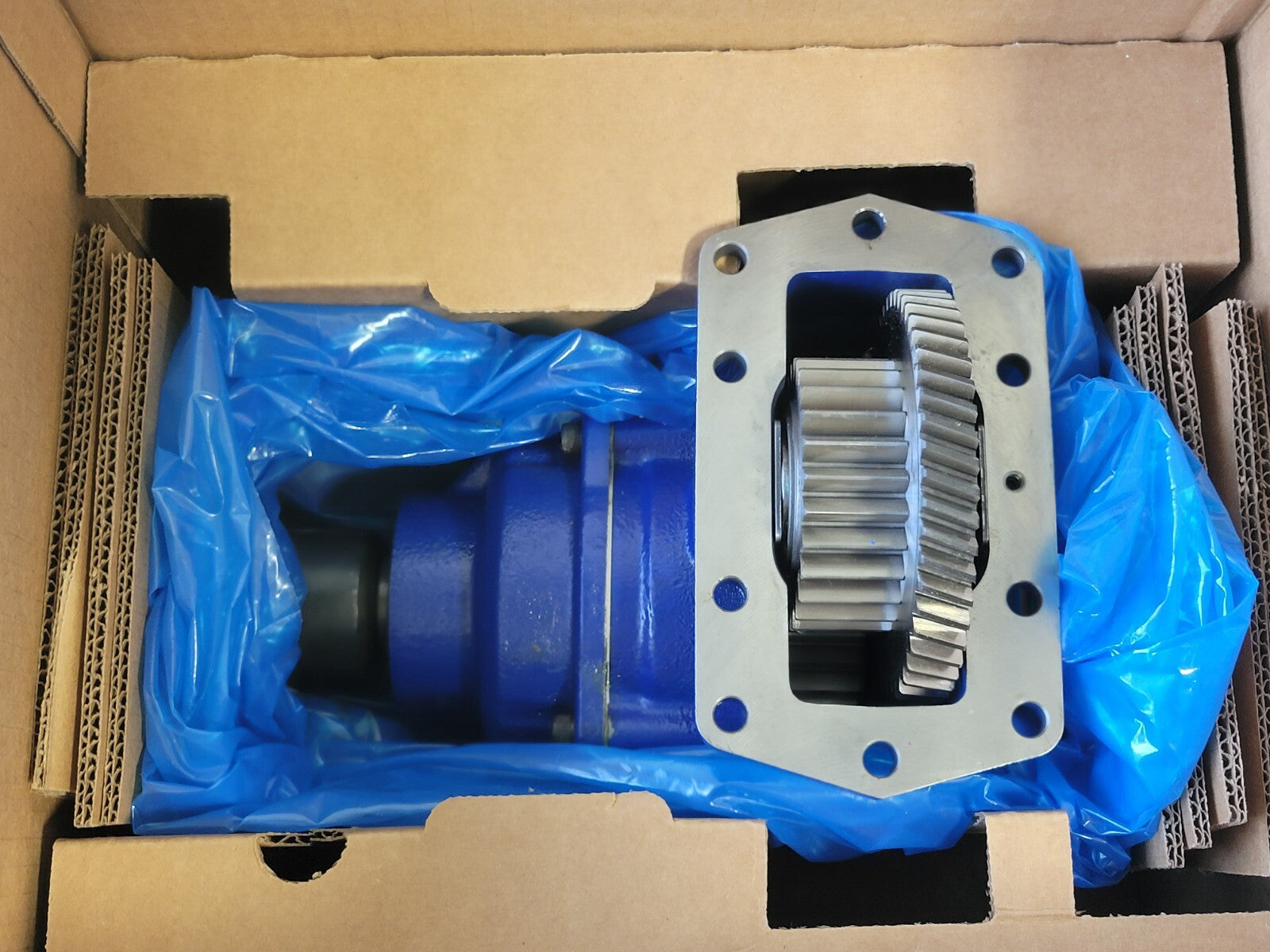 Mechanical component in a cardboard box with blue plastic wrap