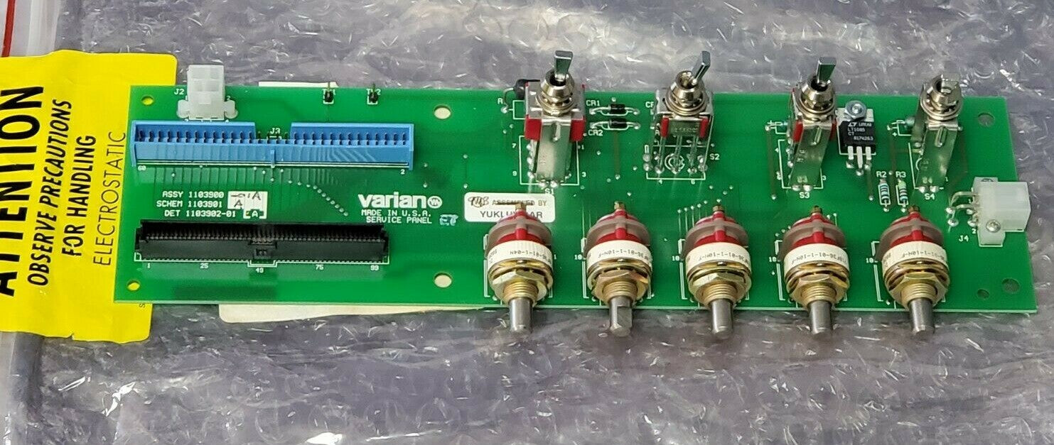 Electronic circuit board with various components on a gray surface, featuring a yellow caution label.